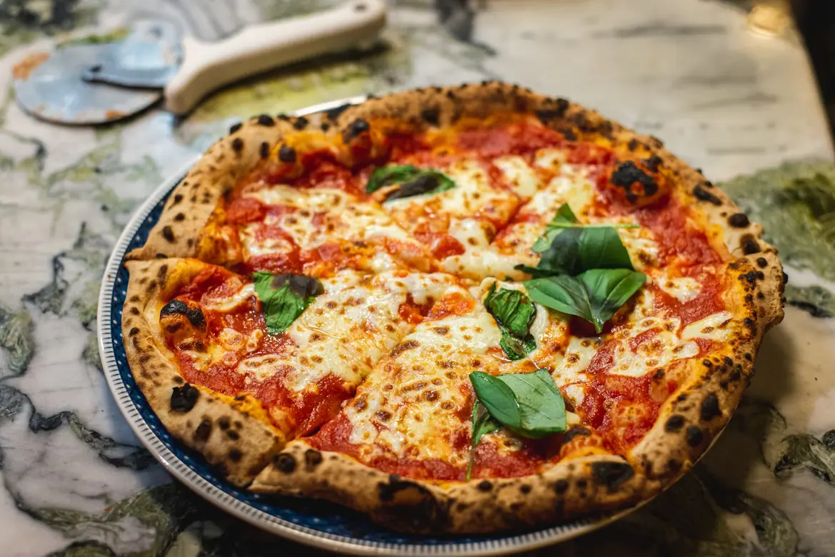 Delightful Italian pasta and pizza served by the scenic Venetian canal under sunny skies.